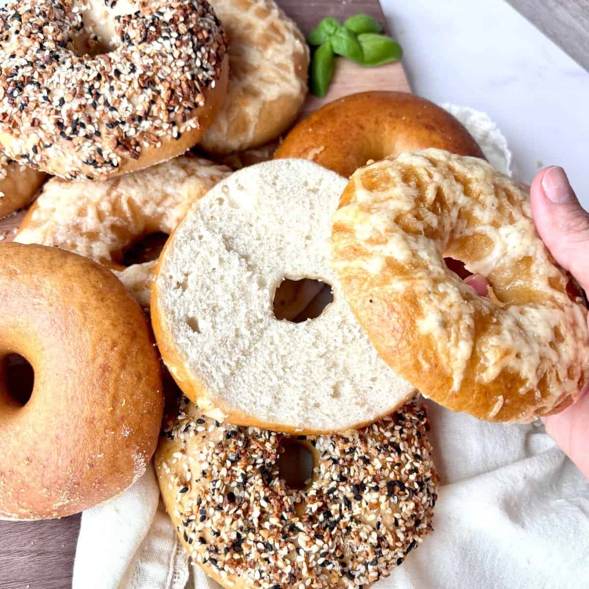 a pile of sourdough bagels with one sliced on top